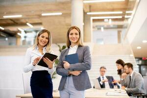 twee jong bedrijf Dames op zoek Bij financieel resultaten Aan digitaal tablet in voorkant van hun team Bij de kantoor foto