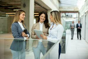 drie jong bedrijf Dames hebben een discussie in de kantoor gang foto