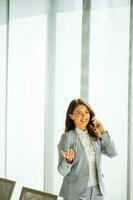 jong vrouw met mobiel telefoon door de venster foto