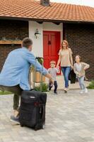 vader kwam huis van de reis en zoon, dochter en vrouw rennen naar ontmoeten hem foto