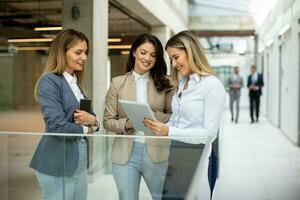 drie jong bedrijf Dames hebben een discussie in de kantoor gang foto