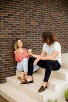 glimlachen jong paar in liefde zittend in voorkant van huis steen muur foto