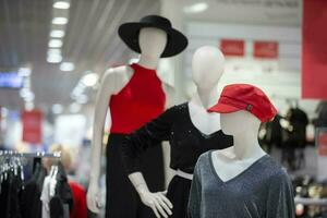 een groep van etalagepoppen in een op te slaan. drie Dames mannequin in elegant kleren. kleding uitverkoop concept. foto