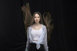 mooi brunette met lang vliegend haar- Aan een donker achtergrond. foto