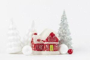 Kerstmis tafereel, miniatuur datsja dorp. Kerstmis weinig rood huizen, hert en besneeuwd Spar bomen Aan een wit achtergrond. feestelijk modern decoraties. foto