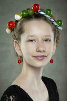 portret van een grappig tiener- meisje met een krans van snoepgoed Aan haar hoofd. foto