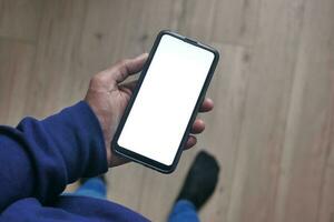 pov schot van jong Mens hand- gebruik makend van slim telefoon met wit scherm foto