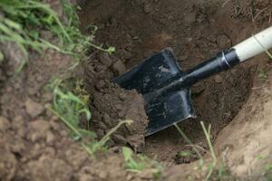 een ijzer Schep in een gat in de grond. hand- grondwerken. foto