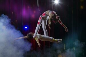circus acrobaten gymnasten uitvoeren Aan een stadium donker achtergrond. foto
