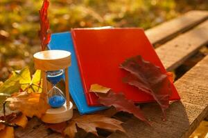 herfst tijd thema, zandloper Aan gedaald bladeren in divers kleuren met kopiëren ruimte. foto