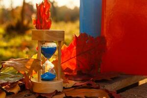 herfst tijd thema, zandloper Aan gedaald bladeren in divers kleuren met kopiëren ruimte. foto