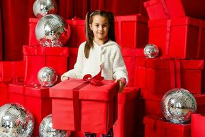 vrolijk schattig weinig kind meisje met Geschenk. weinig meisje is tussen de Kerstmis geschenken. foto