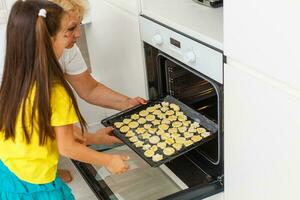 weinig meisje maken koekjes Bij de komst tijd. foto