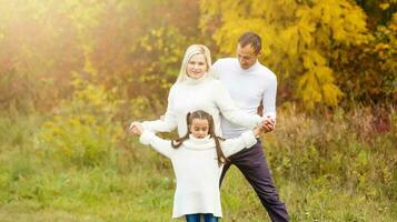 afbeelding van lief familie in herfst park, jong ouders met mooi hoor aanbiddelijk dochter spelen buitenshuis, hebben pret Aan achtertuin in val, gelukkig familie genieten herfst- natuur foto