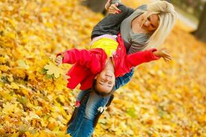 gelukkig familie moeder en kind weinig dochter Speel knuffelen Aan herfst wandelen in natuur buitenshuis foto