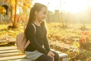 weinig schoolmeisje in de buurt de school. peuter- kind met een rugzak Aan zijn eerste dag Bij school- of kleuterschool. terug naar school. kind onderwijs. herfst foto