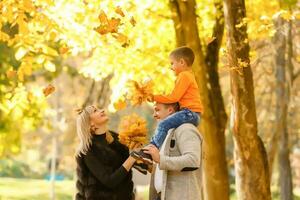 gelukkig familie moeder vader en baby Aan herfst wandelen in de park foto