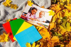 weinig meisjes in een foto boek liggen in herfst bladeren