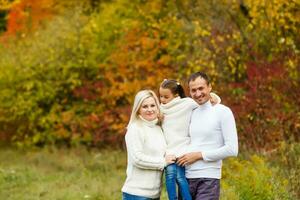 afbeelding van lief familie in herfst park, jong ouders met mooi hoor aanbiddelijk dochter spelen buitenshuis, hebben pret Aan achtertuin in val, gelukkig familie genieten herfst- natuur foto