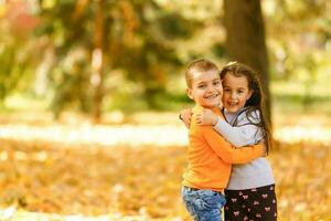 kinderen spelen met herfst gevallen bladeren in park foto