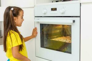 weinig meisje maakt koekjes van de deeg in de keuken Bij huis foto