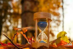 herfst tijd thema, zandloper Aan gedaald bladeren in divers kleuren met kopiëren ruimte. foto