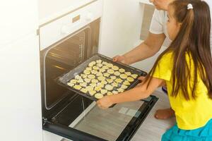 weinig meisje maakt koekjes van de deeg in de keuken Bij huis foto