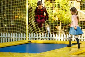 gelukkig school- meisje jumping Aan trampoline in de herfst park foto