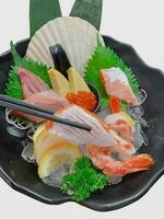 hand- Holding Zalm sashimi met eetstokjes. Japans reeks maaltijd. Zalm, vis, garnaal, schulp foto