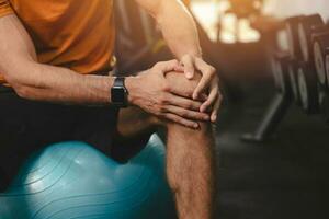 detailopname Mens hand- Holding ondersteuning knie blessure. sport mannetje pijn lijden van knieschijf of knie pet ligament pijn foto