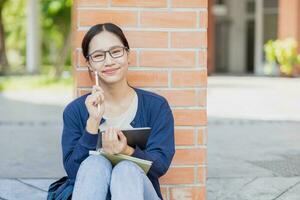 Universiteit Aziatisch tiener meisje zittend gelukkig glimlach in school- campus. leerling met tablet computer. foto