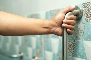 Aziatisch ouderen vrouw gebruik badkamer omgaan met veiligheid in toilet, gezond sterk medisch concept. foto