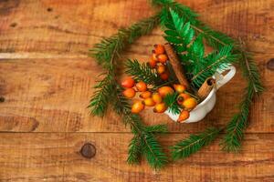 winterse, warme sfeer. een compositie met een kopje met sparren takken en rozenbottels op een houten ondergrond foto