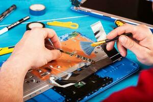 tovenaar repareert laptop met gereedschap en handen op de blauwe houten tafel. bovenaanzicht foto