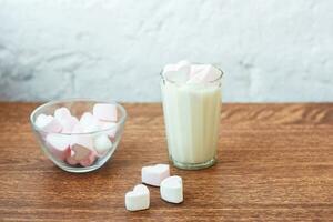 transparant bord met hartvormige marshmallows en een glas verse melk op tafel. ontbijt. zachte combinatie foto