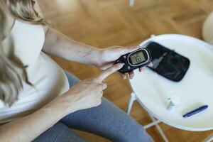 bloed suiker testen Bij huis. zwanger vrouw controle bloed suiker niveau Bij huis. diabetisch controle bloed suiker niveaus. zwanger vrouw controle bloed suiker niveau door glucometer en test streep Bij huis foto