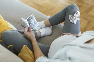 zwanger vrouw Holding echografie afbeelding. concept van zwangerschap, Gezondheid zorg, gynaecologie, geneesmiddel. jong moeder aan het wachten van de baby. detailopname, kopiëren ruimte, binnenshuis. foto