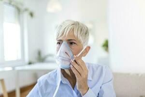 ziek ouderen vrouw maken inademing, geneeskunde is de het beste geneesmiddel. ziek senior vrouw vervelend een zuurstof masker en ondergaan behandeling voor covid19. senior vrouw met een inhalator foto