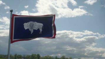Wyoming vlag Aan een vlaggenmast golvend in de wind, blauw lucht achtergrond. 3d illustratie foto