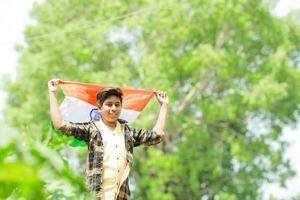 Indisch jongen Holding nationaal vlag in boerderij, gelukkig jongen, nationaal vlag foto