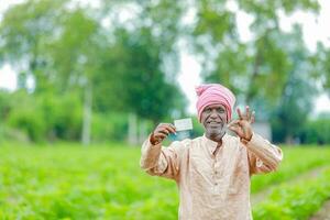 Indisch boer Holding gullak in hand, besparing concept, gelukkig arm boer foto