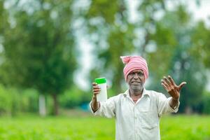 Indisch gelukkig boer Holding leeg fles in handen, gelukkig boer tonen wit fles foto