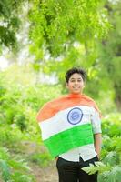 Indisch jongen Holding nationaal vlag in boerderij, gelukkig jongen, nationaal vlag foto