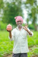 Indisch boer Holding gullak in hand, besparing concept, gelukkig arm boer foto