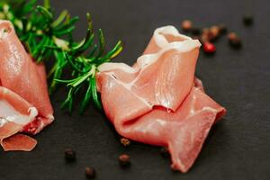 stukken van droog varkensvlees Jamon prosciutto met olijven Aan een zwart bord foto