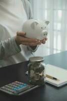 vrouw hand- zetten geld munt in varkentje voor besparing geld rijkdom en financieel concept. foto