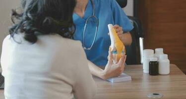 dokter en geduldig pratend terwijl zittend Bij de bureau in ziekenhuis kantoor, detailopname van menselijk handen. geneeskunde en Gezondheid zorg concept foto