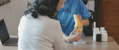 dokter en geduldig pratend terwijl zittend Bij de bureau in ziekenhuis kantoor, detailopname van menselijk handen. geneeskunde en Gezondheid zorg concept foto