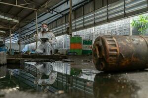 noodgeval verontreiniging fabriek concept. vrouw chemicus vervelend ppe en gas- masker inspecteren olie Aan fabriek verdieping foto