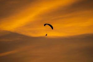 het silhouet van de paramotor bij zonsondergang foto